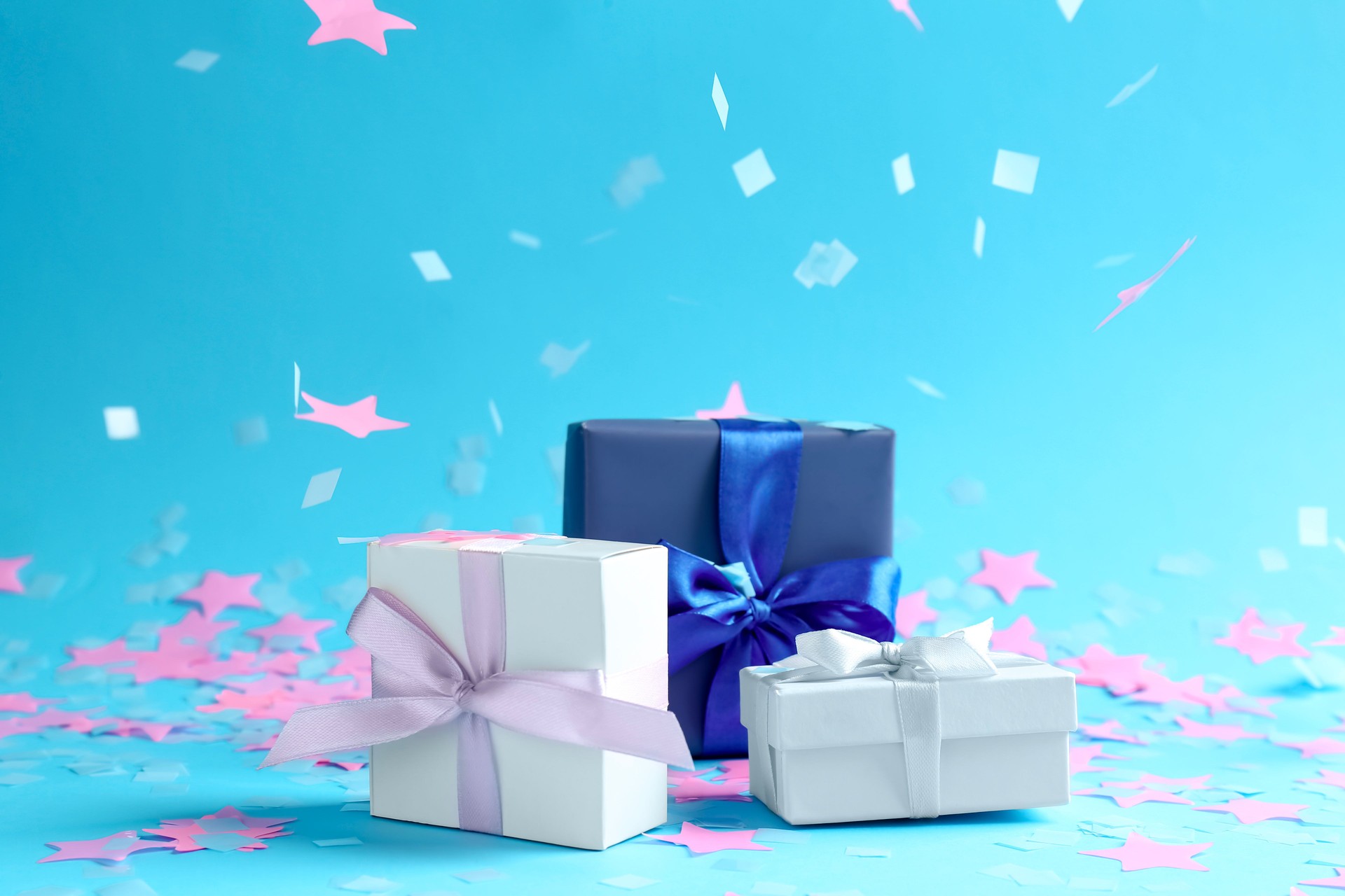 Beautiful confetti falling on gift boxes against light blue background